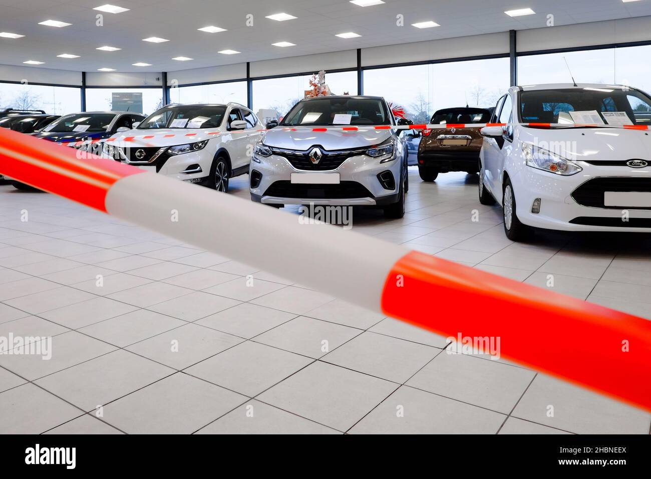 cars in a showroom at a point of sale are shielded with red white ribbons the showroom is prohibited area for customers with the recent covid lockdown Stock Photo