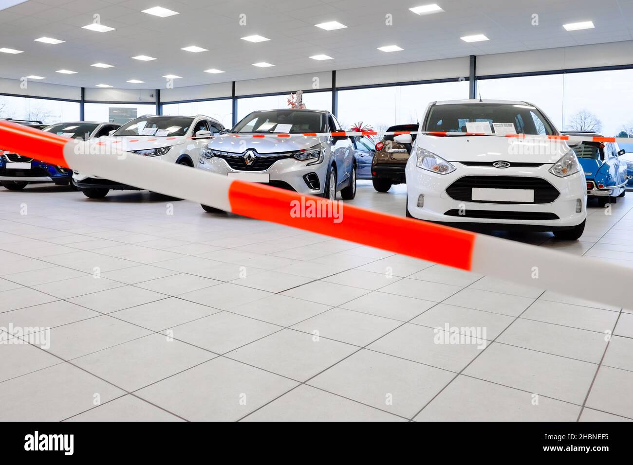 cars in a showroom at a point of sale are shielded with red white ribbons the showroom is prohibited area for customers with the recent covid lockdown Stock Photo