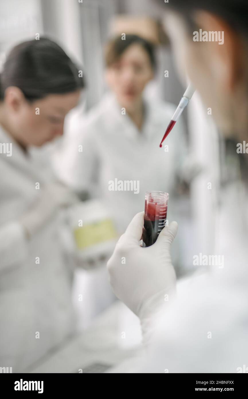 Group of scientists working with liquid test tube samples in laboratory ...