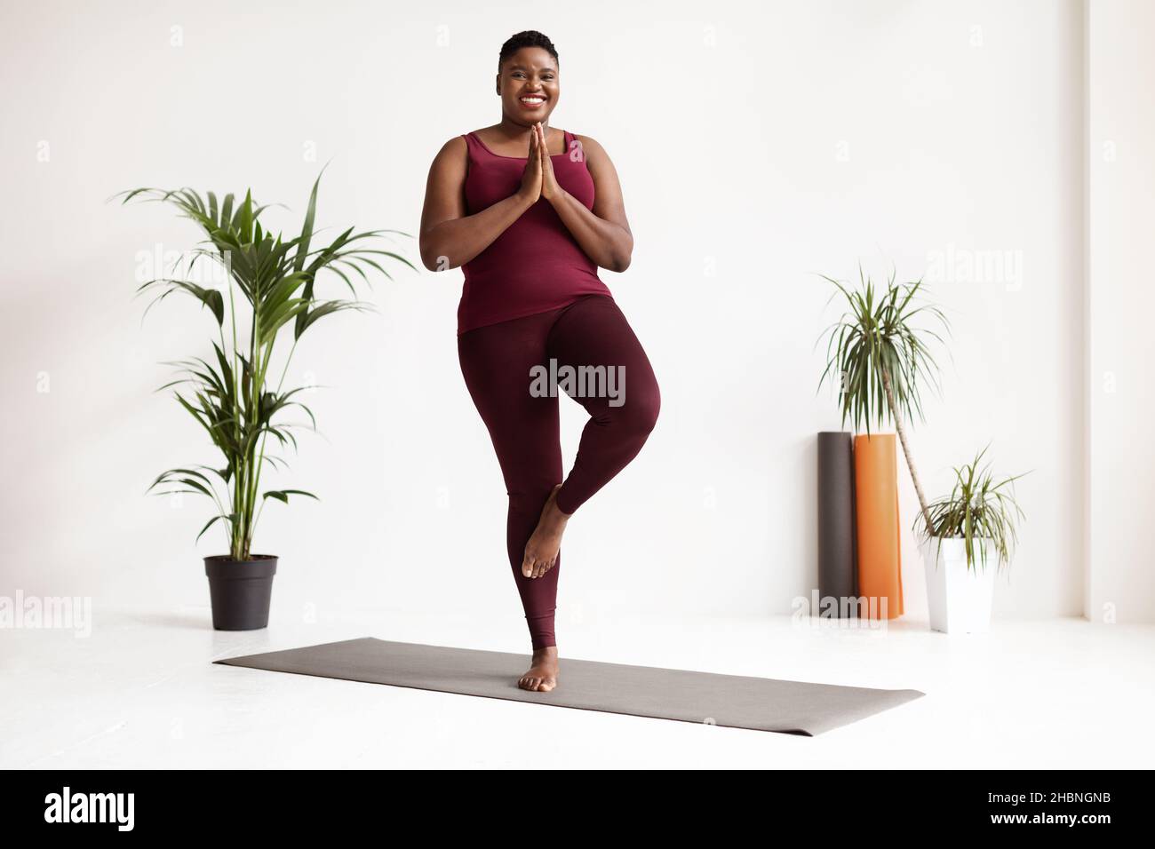 Cheerful plus size black woman doing yoga on sports mat at home, free space  Stock Photo by Prostock-studio
