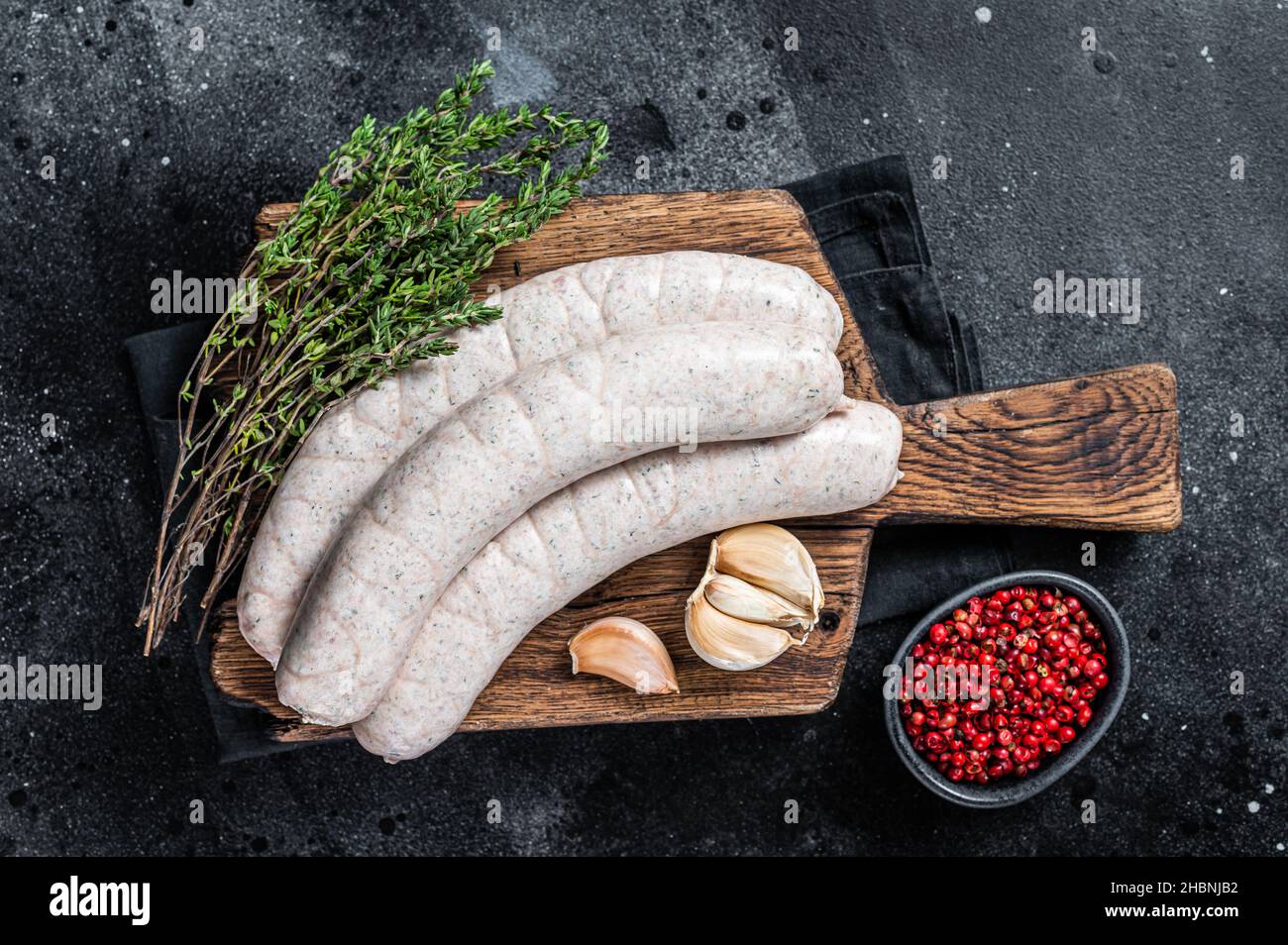 Raw Munich white sausage weisswurst on wooden board. Black background. Top view Stock Photo