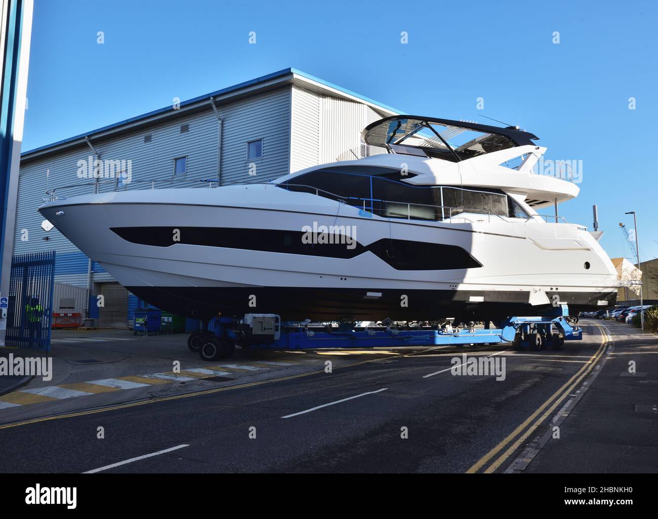 A Sunseeker luxury yacht is moved along a public road on a remotely-controlled motorised trolley in Poole, Dorset. Stock Photo