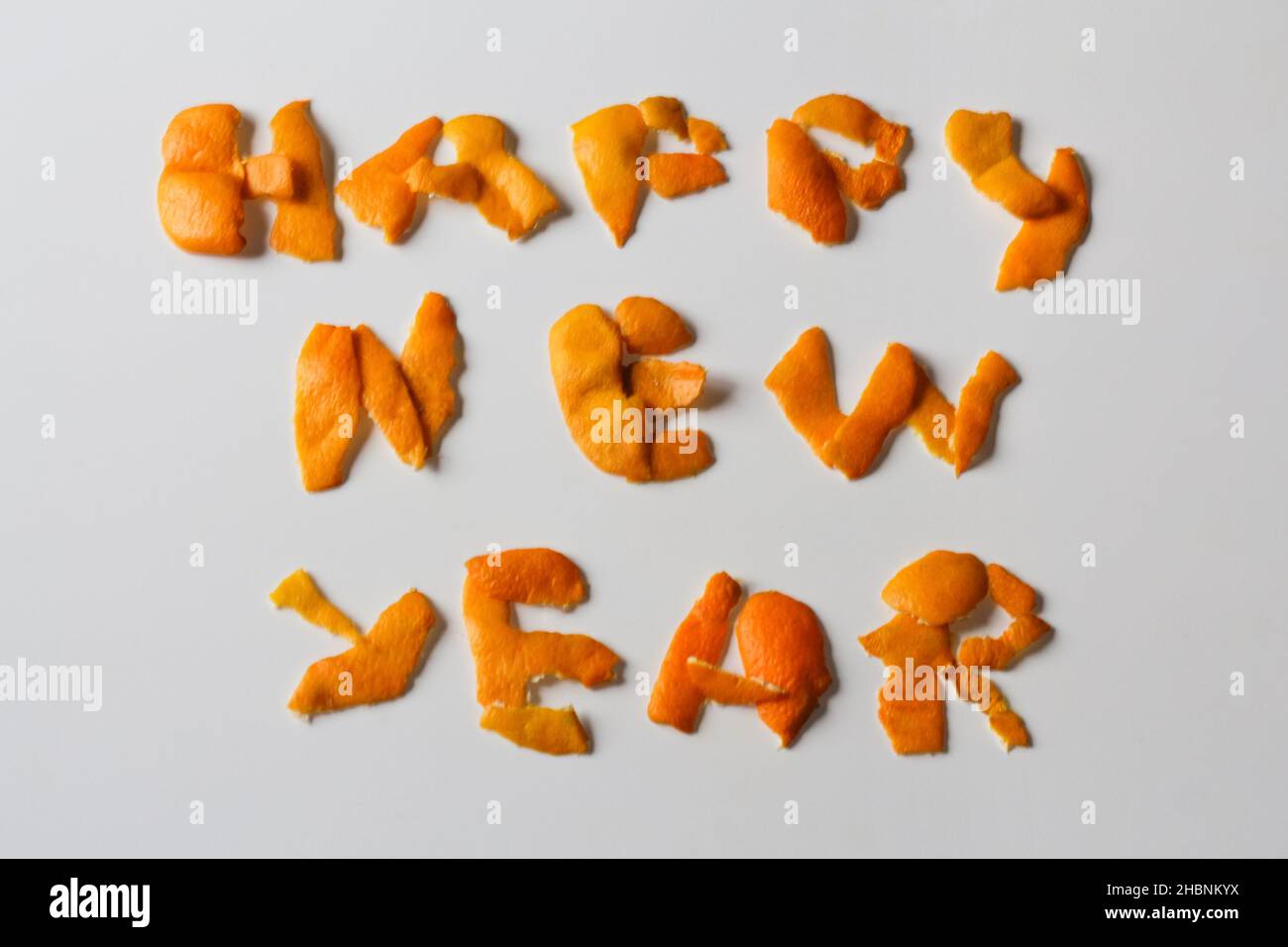 Defocus Happy New year word displayed by orange dry peel on a isolated white background. Decoration for New Year's Eve, concept. Greeting card. Text Stock Photo