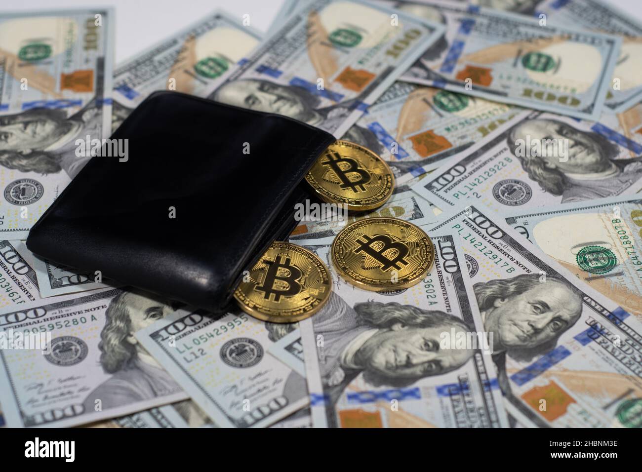 Gold shiny bitcoin crypto currency coins with black wallet on one hundred  dollars, close up photo Stock Photo - Alamy