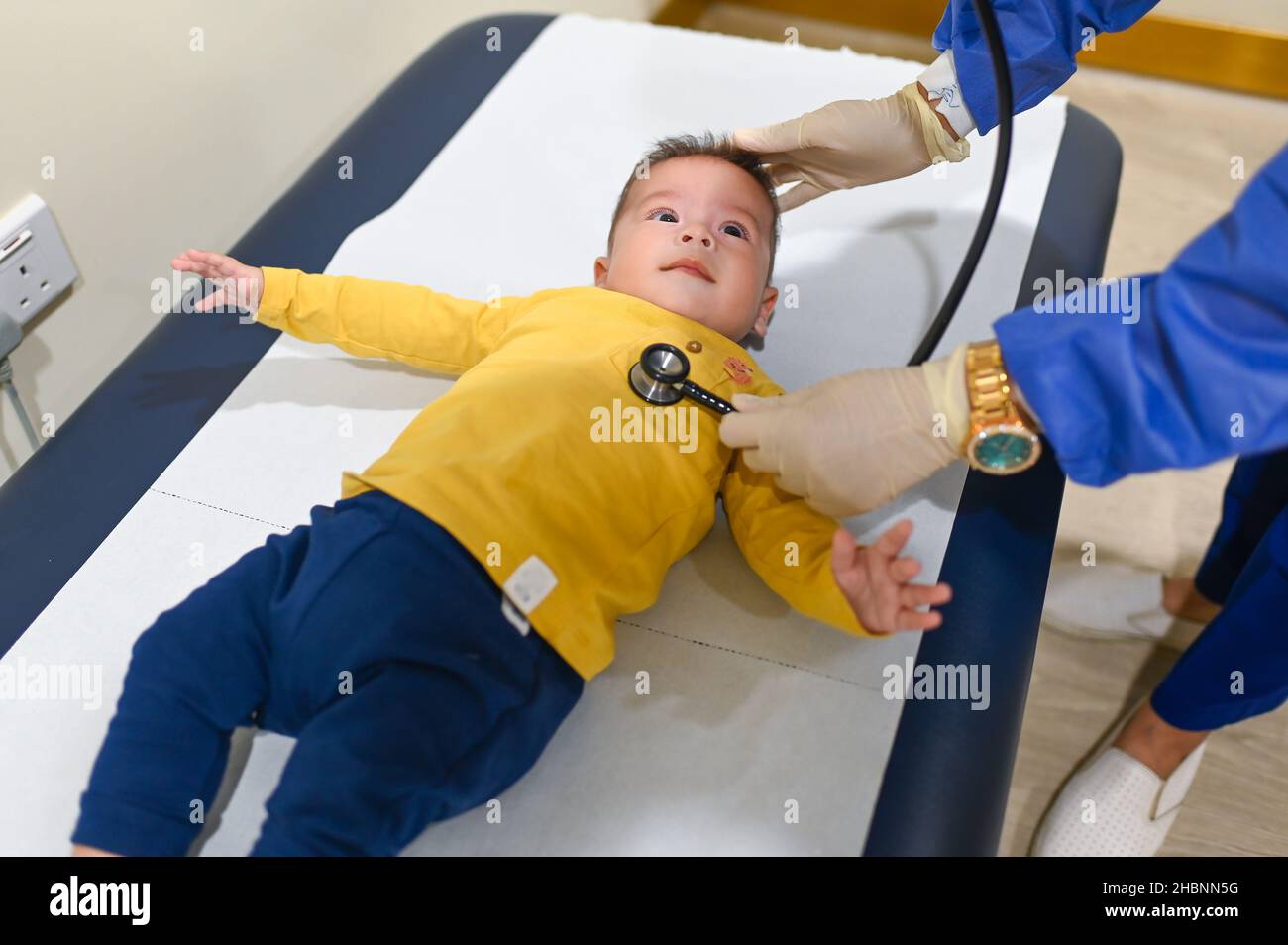 Pediatrician using stethoscope to listen breathing of a 5 months old mixed race baby boy at the doctor office for a routine checkup and physical exam Stock Photo