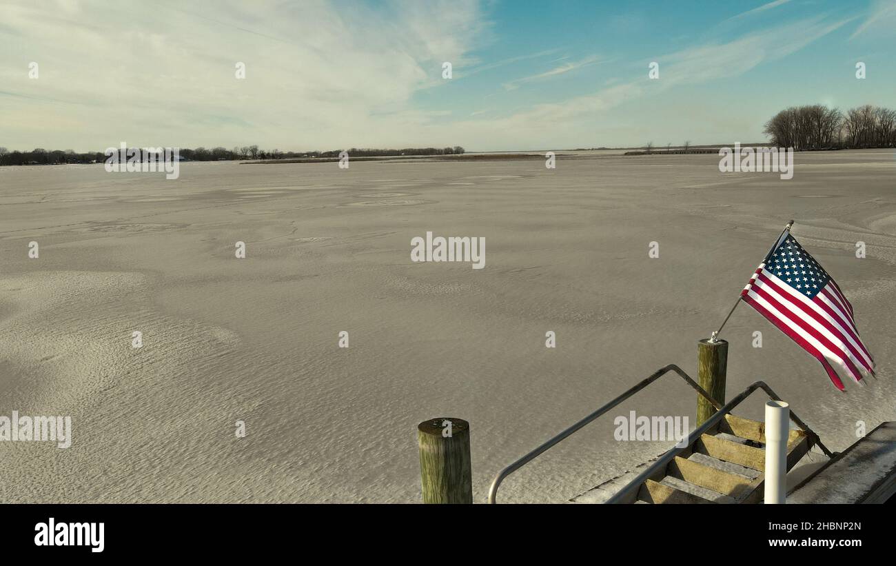 View from the dock of frozen lake Winneconne with American flag in the