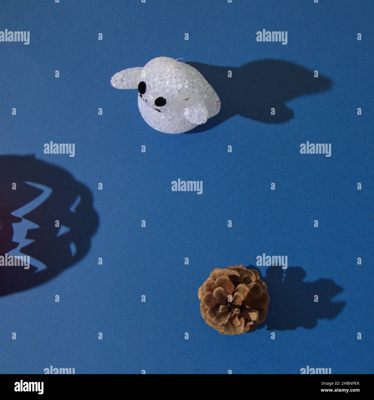 A ghost and a pine cone with shadows, with a shadow of halloween pumpkin on a blue background Stock Photo