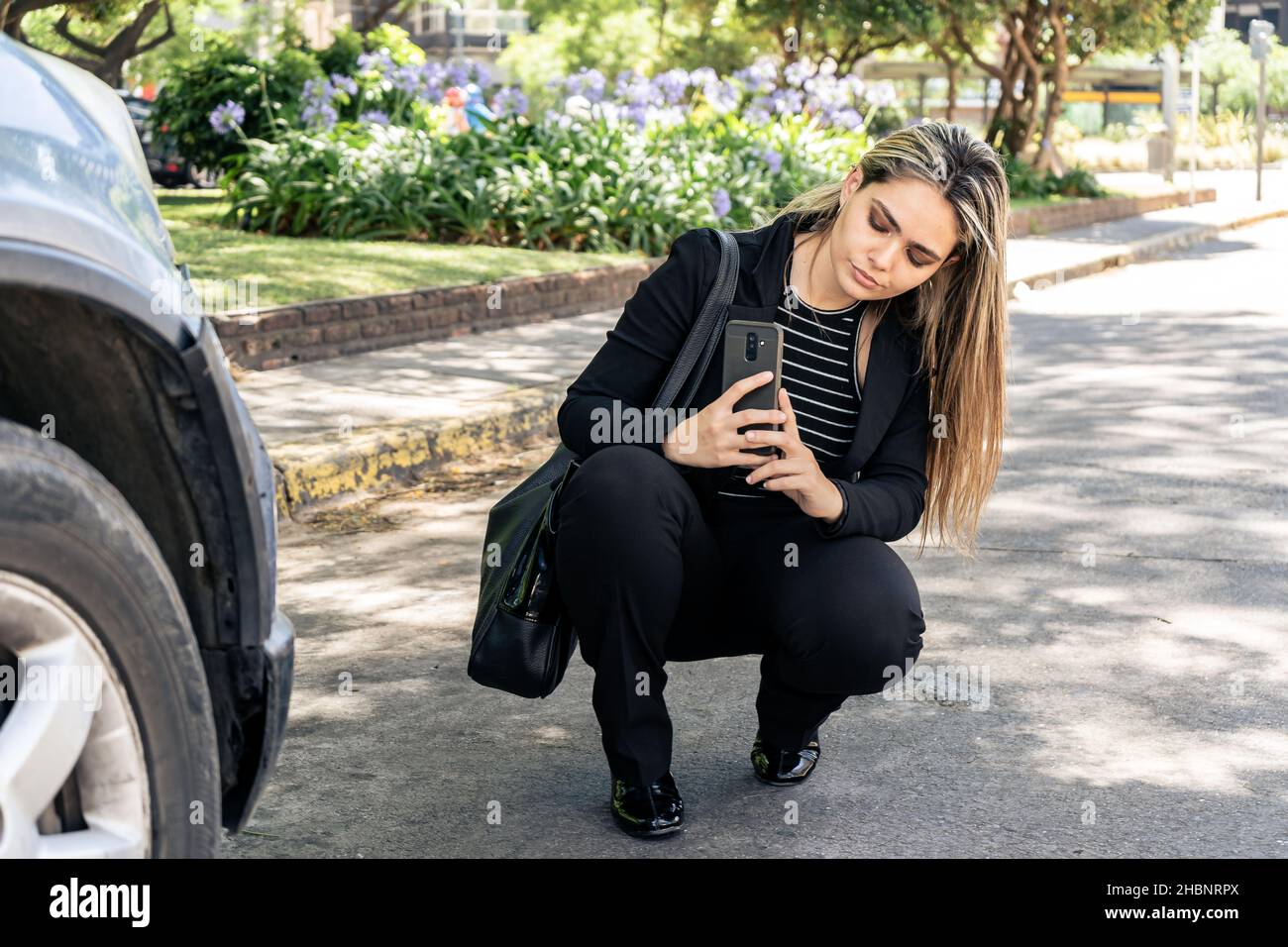 A Business woman takes pictures of crash damage to her car to send to insurance company. Stock Photo
