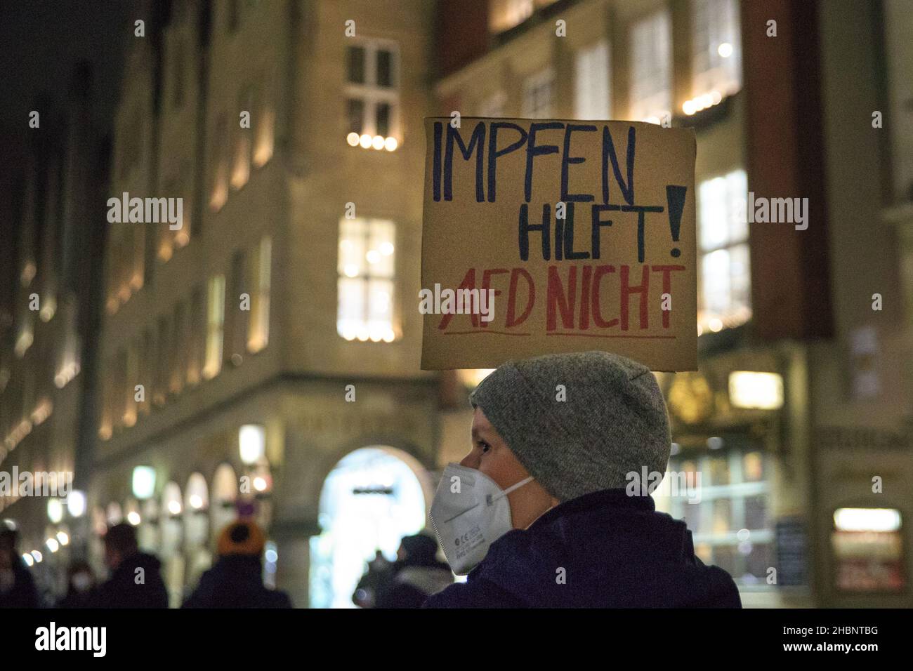 Münster, NRW, Germany. 20th Dec, 2021. A protester with 'Impfen Hilft, AFD Nicht' (vaccinating helps, AFD doesn't) placard. Activists and protesters from several organisations have congregated in the city centre, protesting against conspiracy theories, racism, anti-semitism and social segregation, and for vaccinations. Credit: Imageplotter/Alamy Live News Stock Photo