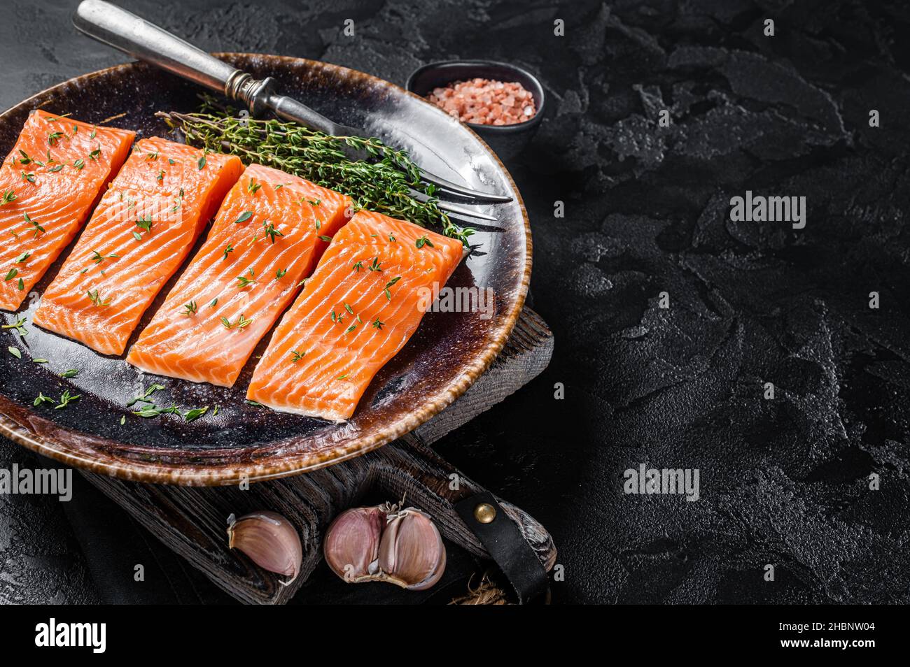 Salmon fillet steaks, raw fish with thyme and herbs. Black background ...