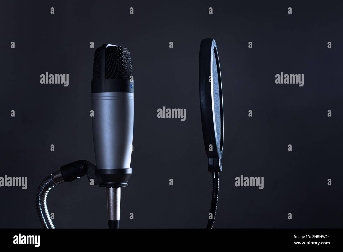 Condenser microphone with pop filter isolated on dark background. Stock Photo