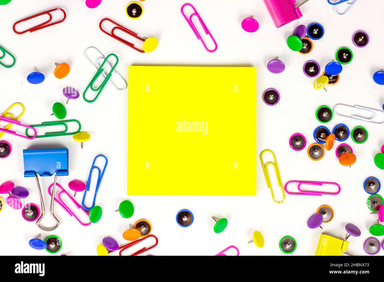 Bright pink, yellow, blue and green stationery accessories for office and education on white background with sticky notes copy space. Stock Photo