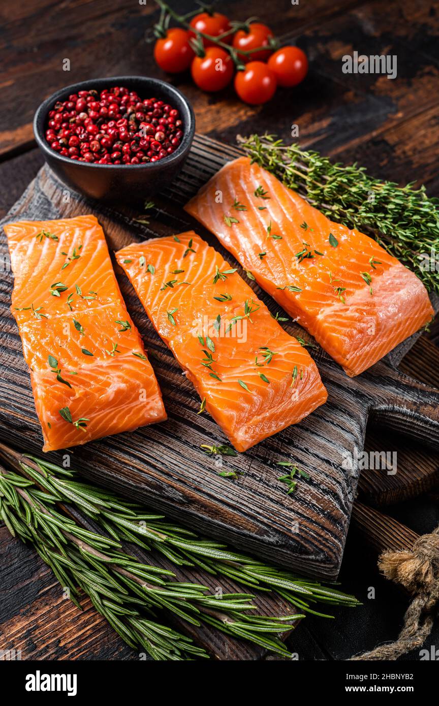 Raw Salmon fillet steaks on wooden board with thyme and rosemary ...