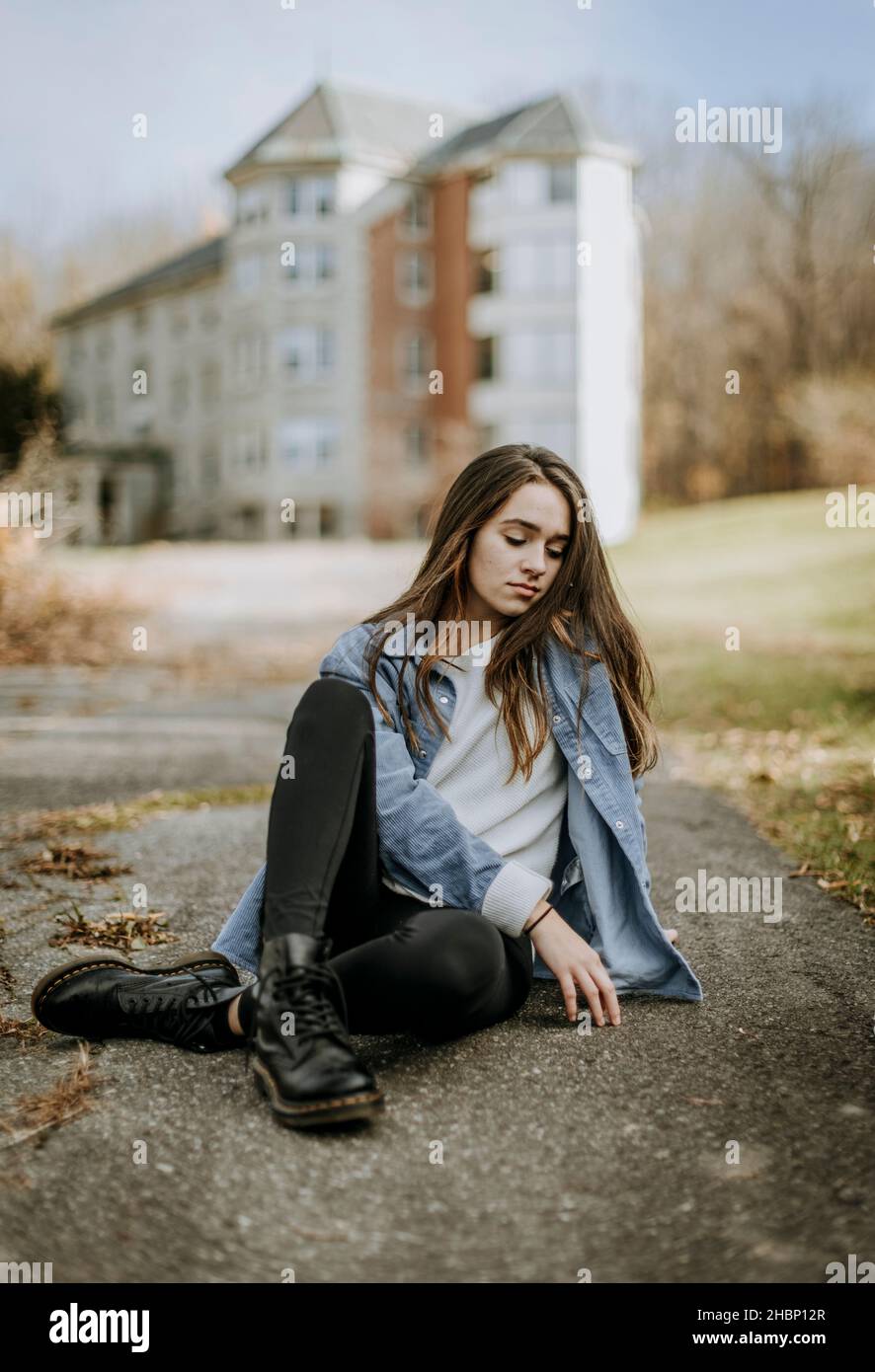 teenager sits on ground pavement looking sad thoughtful depressed Stock Photo