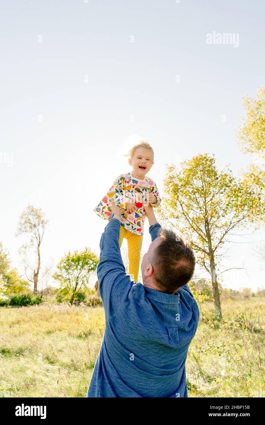 Portrait of a father throwing his toddler daughter into the air Stock Photo