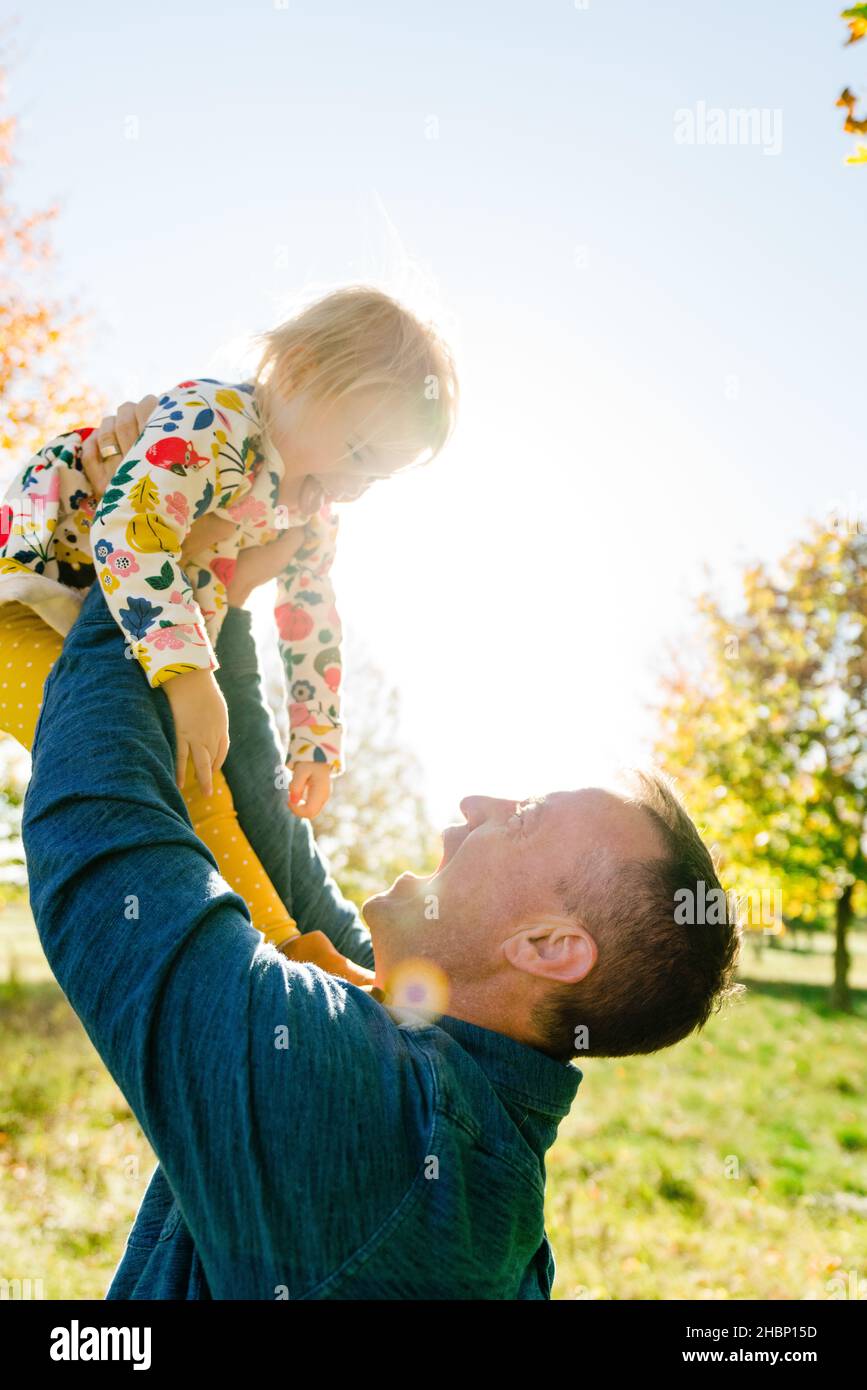 Closeup portrait of a father lifting his toddler child into the air Stock Photo