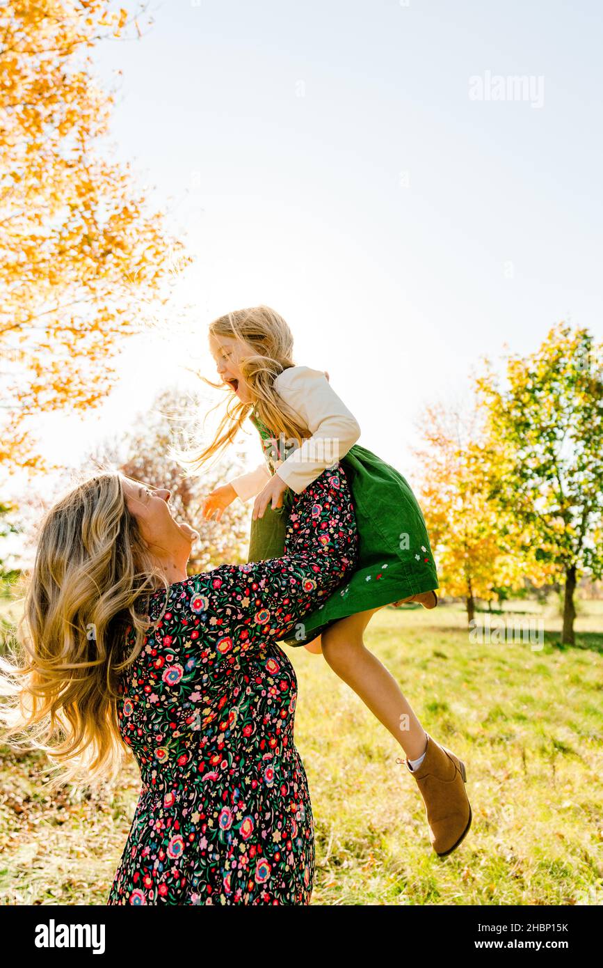 Side view of a mother throwing her daughter into the air Stock Photo