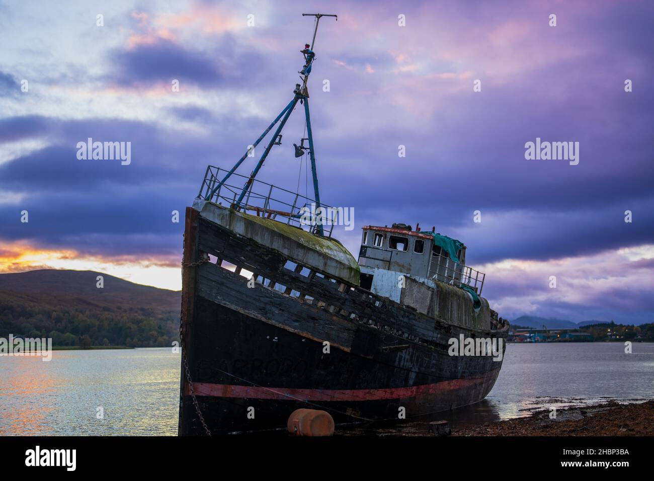 A grounded fishing boat on a beach at Loch Linnhe, with Ben Nevis in the background. Caol, Scotland, UK Stock Photo