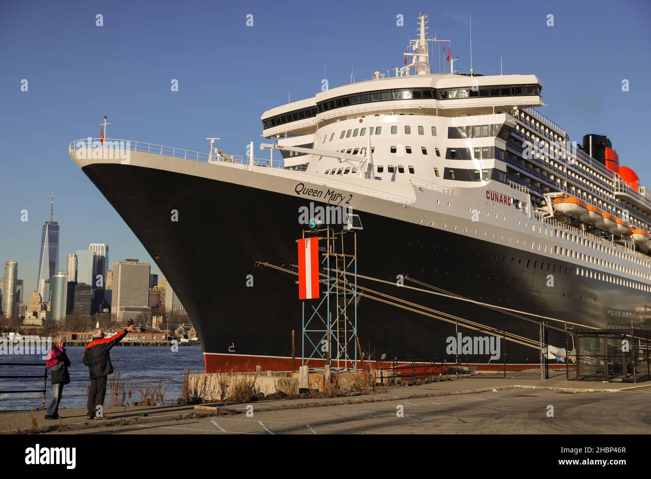People look toward the Queen Mary 2 cruise ship by Cunard Line, owned by Carnival Corporation & plc. as it sits docked at Brooklyn Cruise Terminal in Brooklyn, New York City, U.S., December 20, 2021. REUTERS/Andrew Kelly Stock Photo