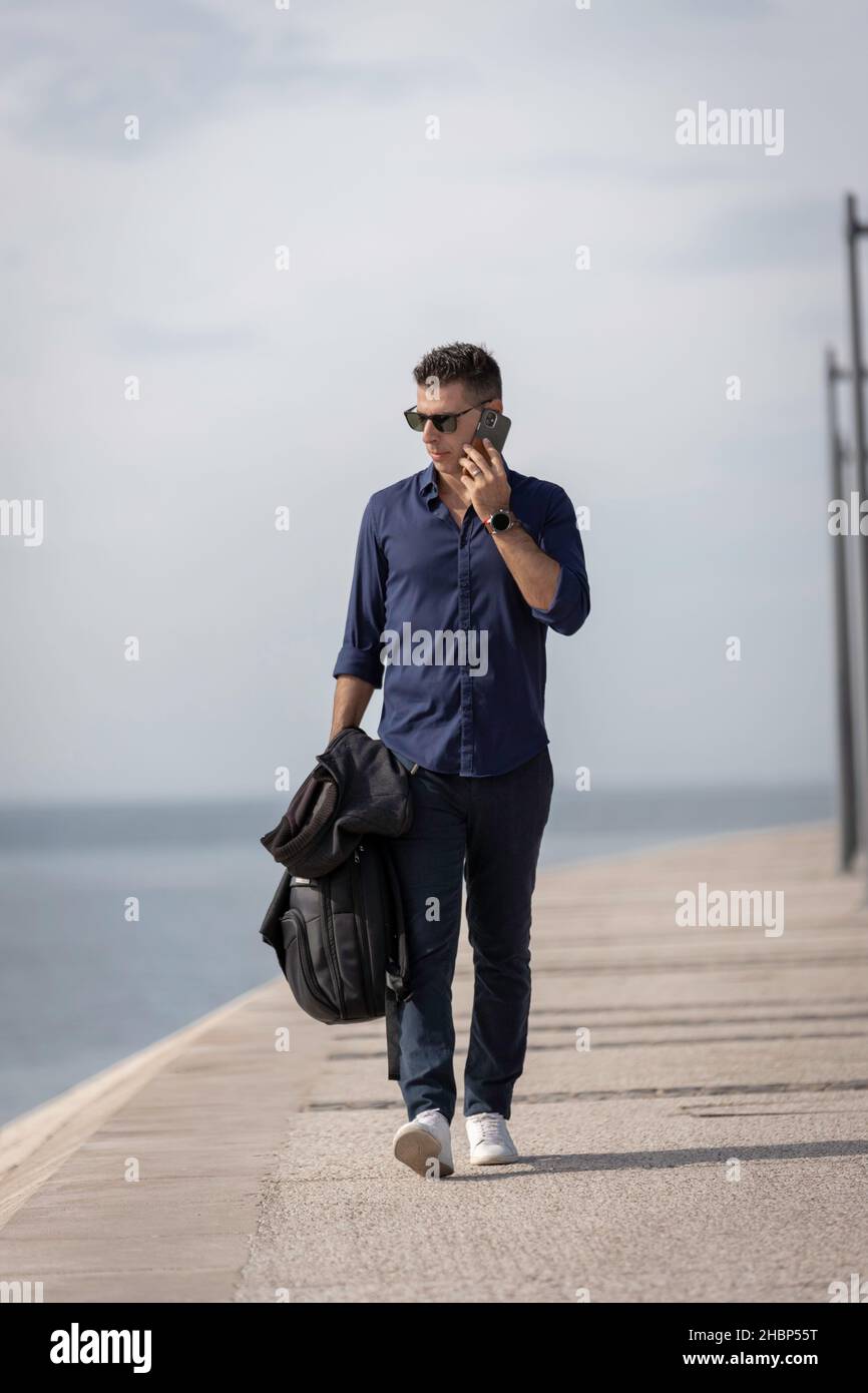 Beautiful and attractive young middle aged man walking alone and using ...