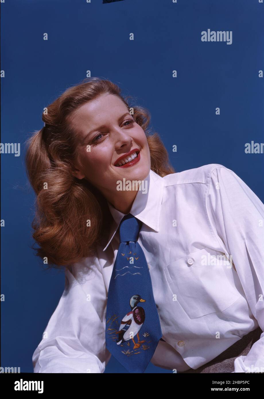 Teen girl in white shirt and blue tie against a blue background Stock Photo