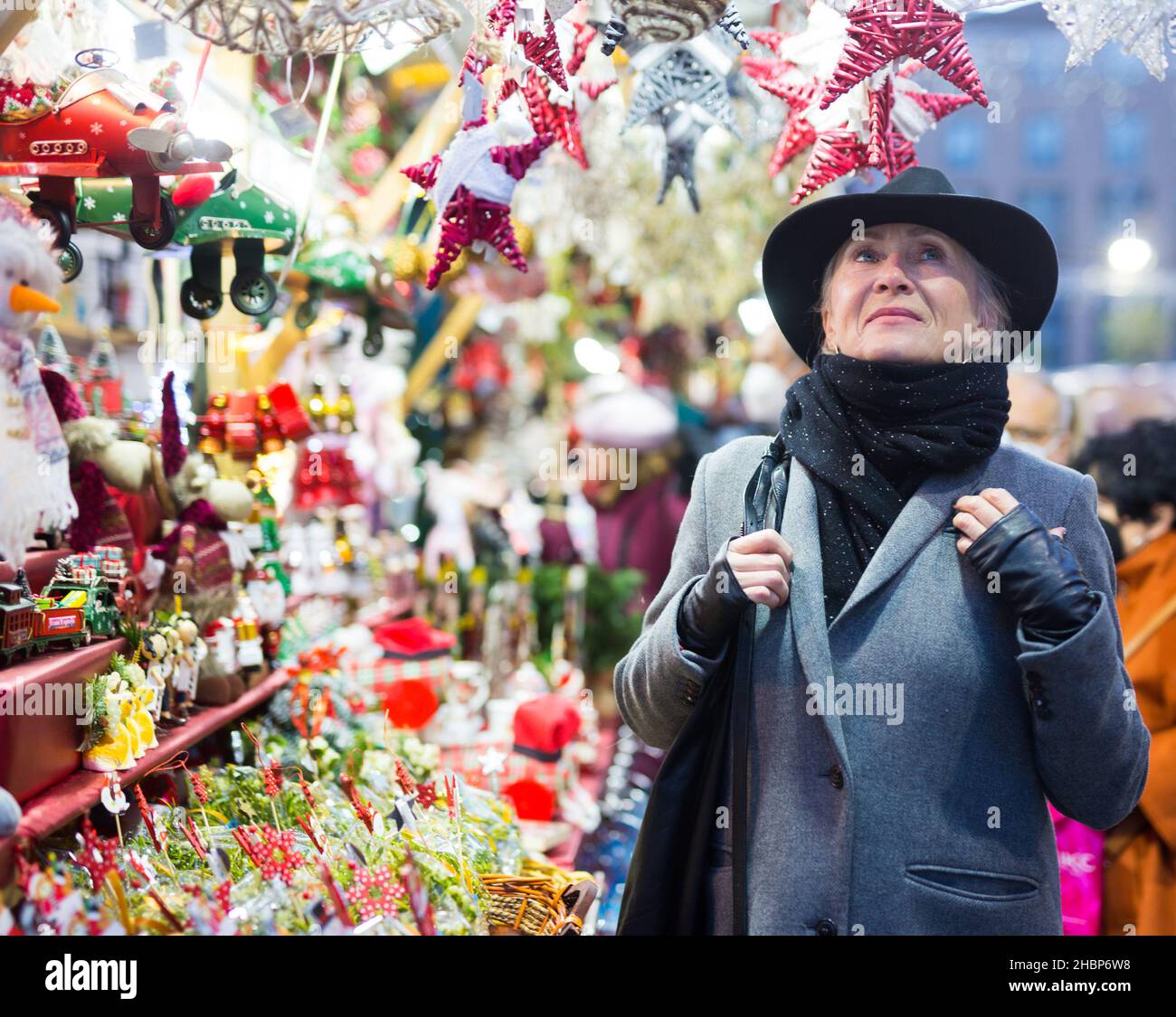 Smiling aged woman walking at traditional city christmas fair Stock Photo
