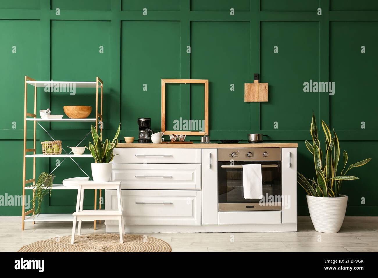 Interior of stylish kitchen with white counter, shelving unit and green