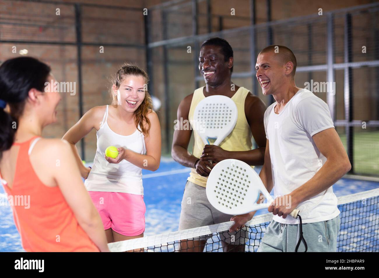 Four smiling men and women with padel rackets posing at court Stock Photo -  Alamy