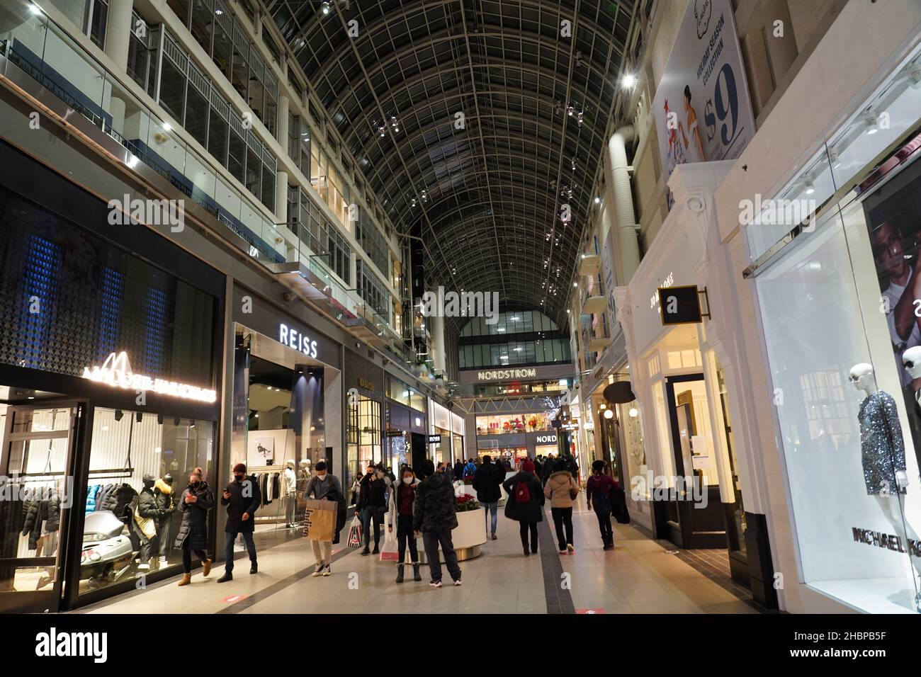 Toronto's Eaton Center is a multi-level indoor mall, with bright Christmas decorations and shoppers wearing face masks due to the pandemic Stock Photo