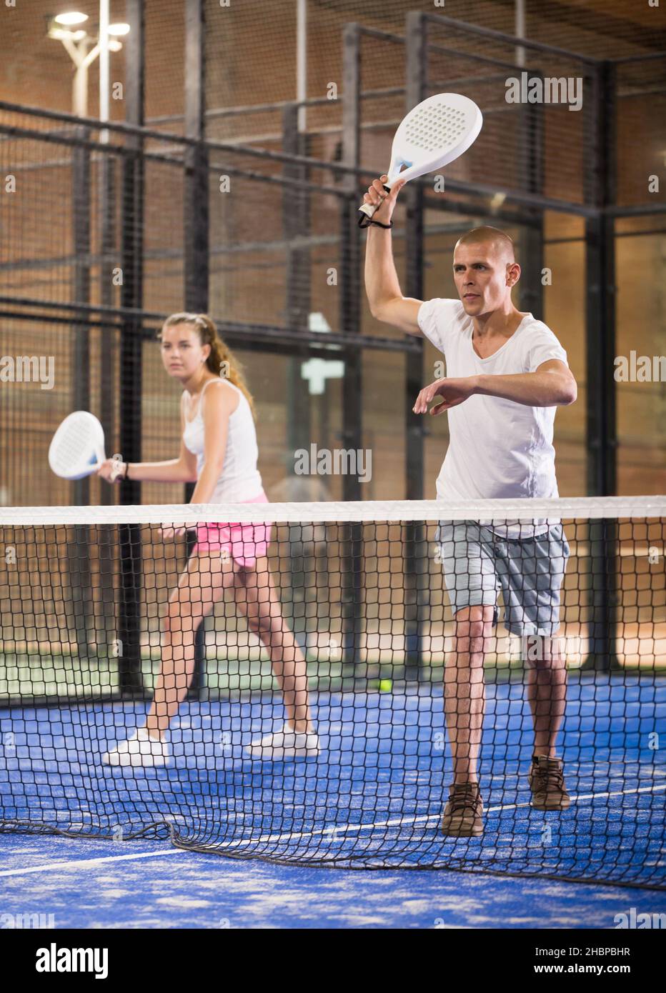 Padel player playing padel in a padel court indoor behind net Stock ...