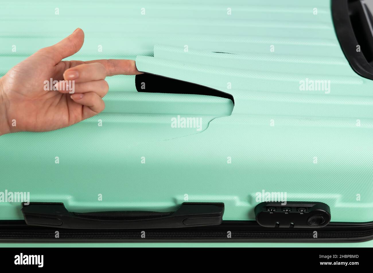 A woman demonstrates a broken suitcase on a white background. Damaged