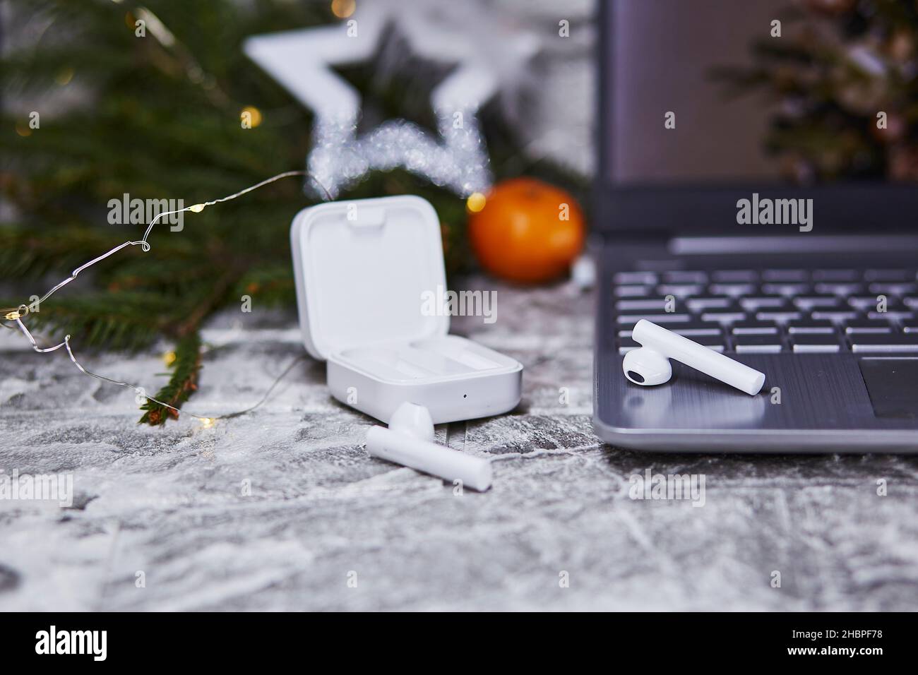 Wireless earphones and laptop near Christmas decorations. Freelance, remote work, taking webinar, calling to family concept. Christmas, New Year's pre Stock Photo