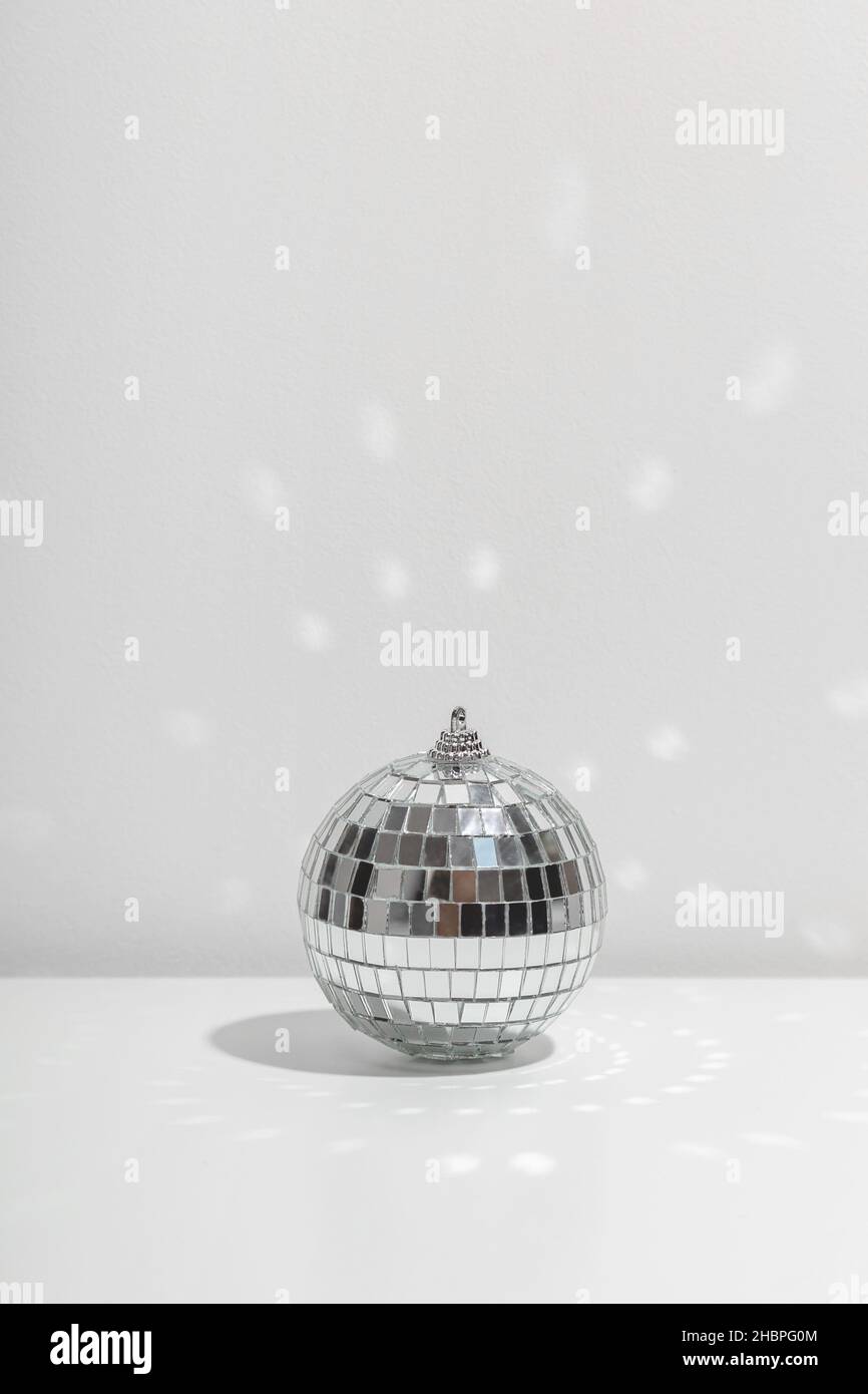 Silver disco ball reflects sunlight on silver background. Stock Photo
