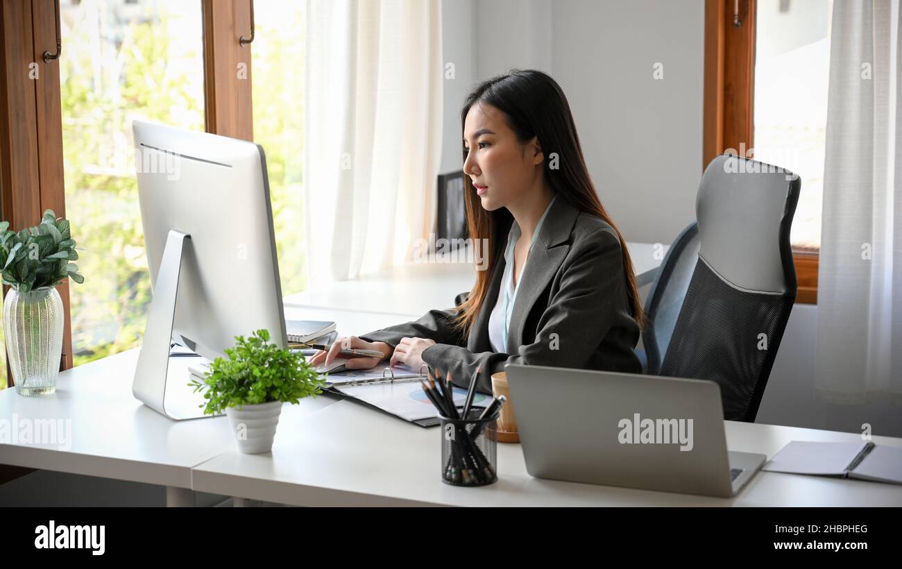 Focused business woman working desktop computer. Female employee pay attention on her project in the office. Female project manager concentrating on h Stock Photo