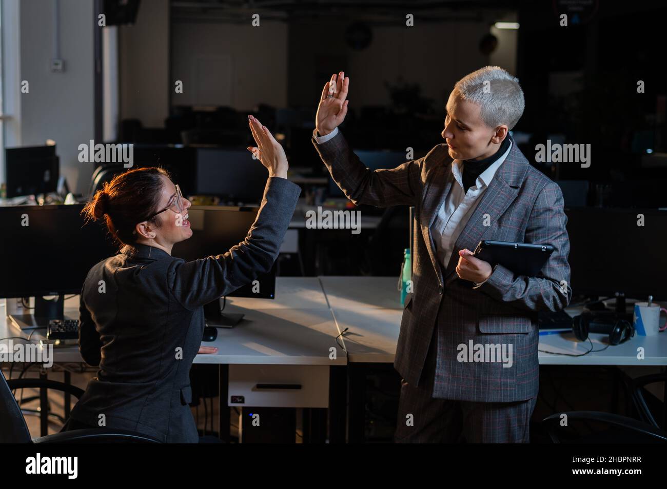 Two business women give a high five in the office. Stock Photo