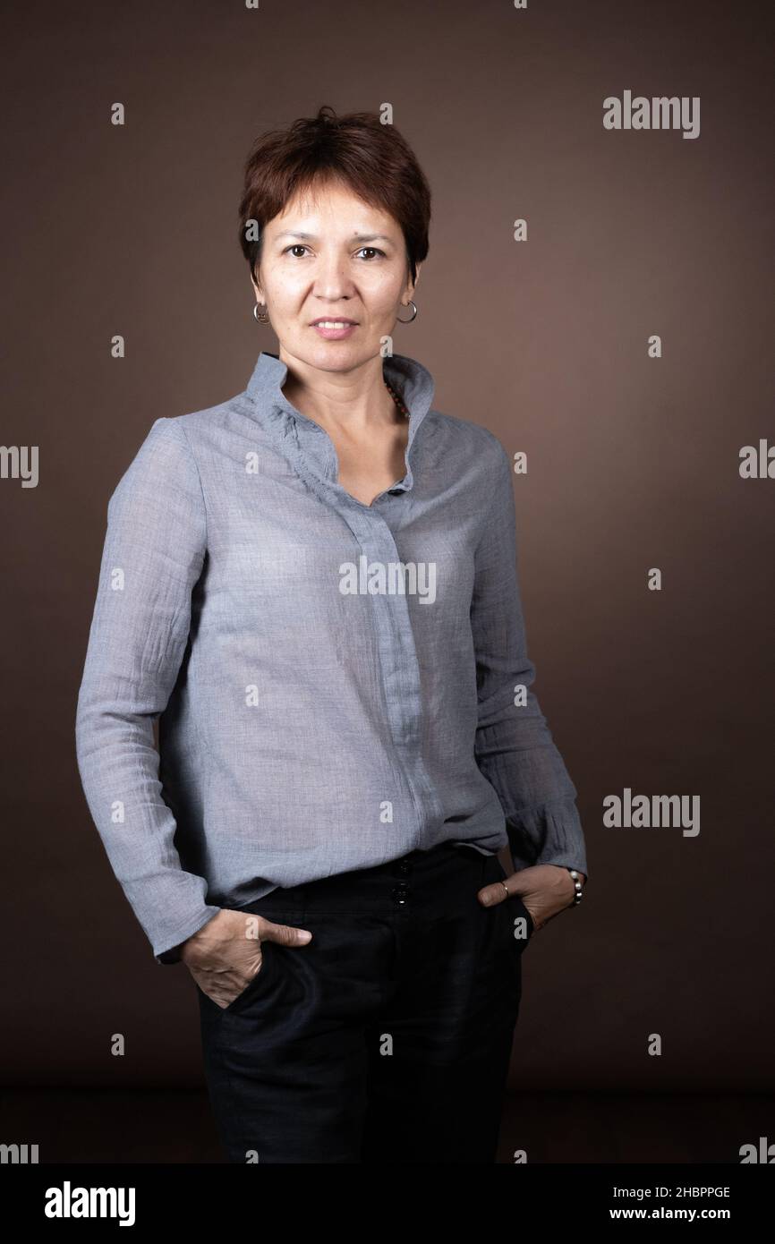 Portrait of mature woman in stylish clothes looking at camera against the grey background Stock Photo