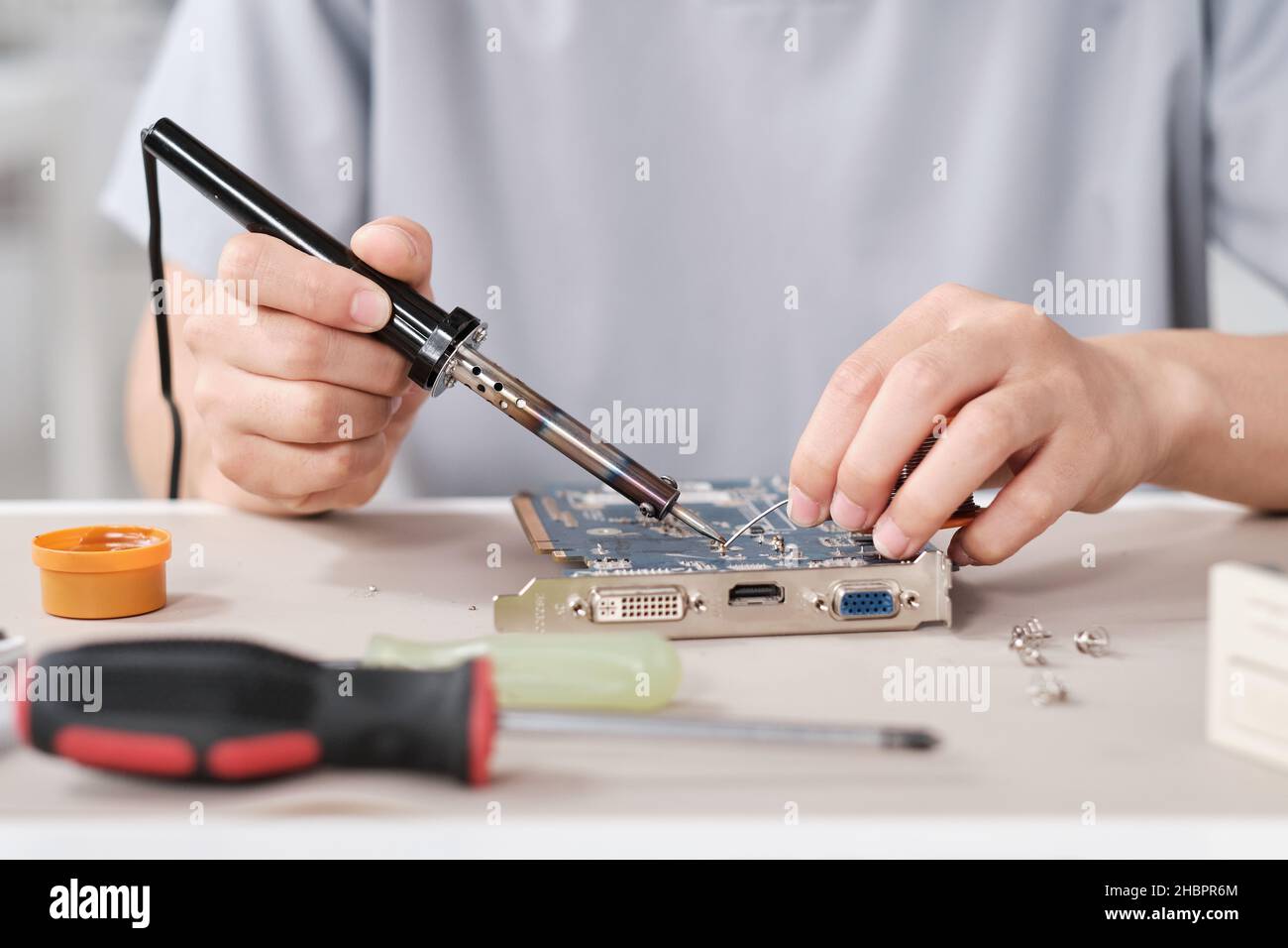 Hands of young contemporary technician with soldering iron repairing motherboard with microchip Stock Photo