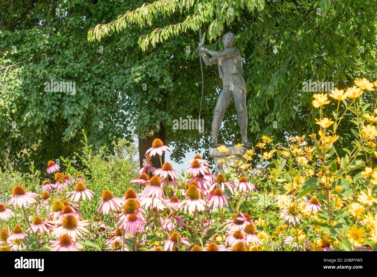 Schnalzerbrunnen in Saaldorf mit den Blumen des Sommers im Vordergrund,  Berchtesgadener Land, Oberbayern Der Bildhauer H. Messner aus Munderfing in Ö Stock Photo
