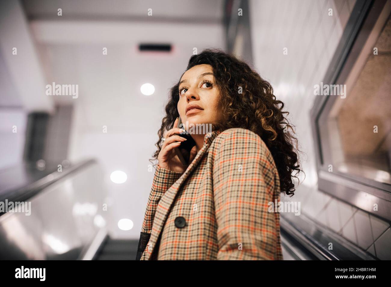 Female professional talking on smart phone at escalator Stock Photo