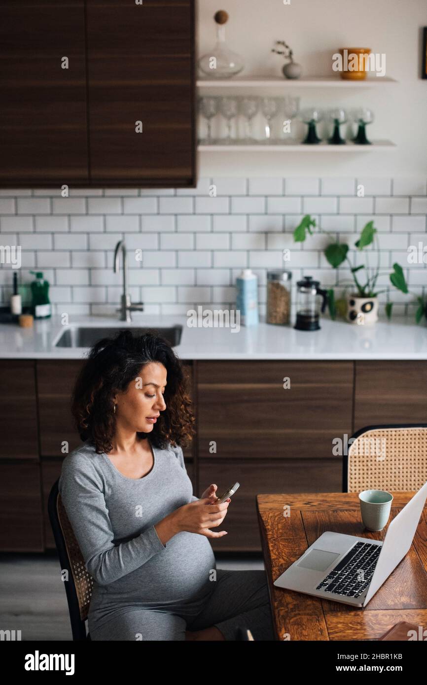 Female freelancer using smart phone while working at home Stock Photo
