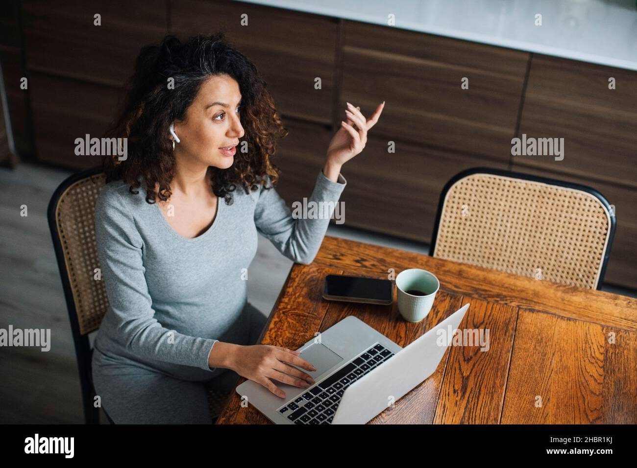 Female entrepreneur talking on bluetooth while working on laptop Stock Photo