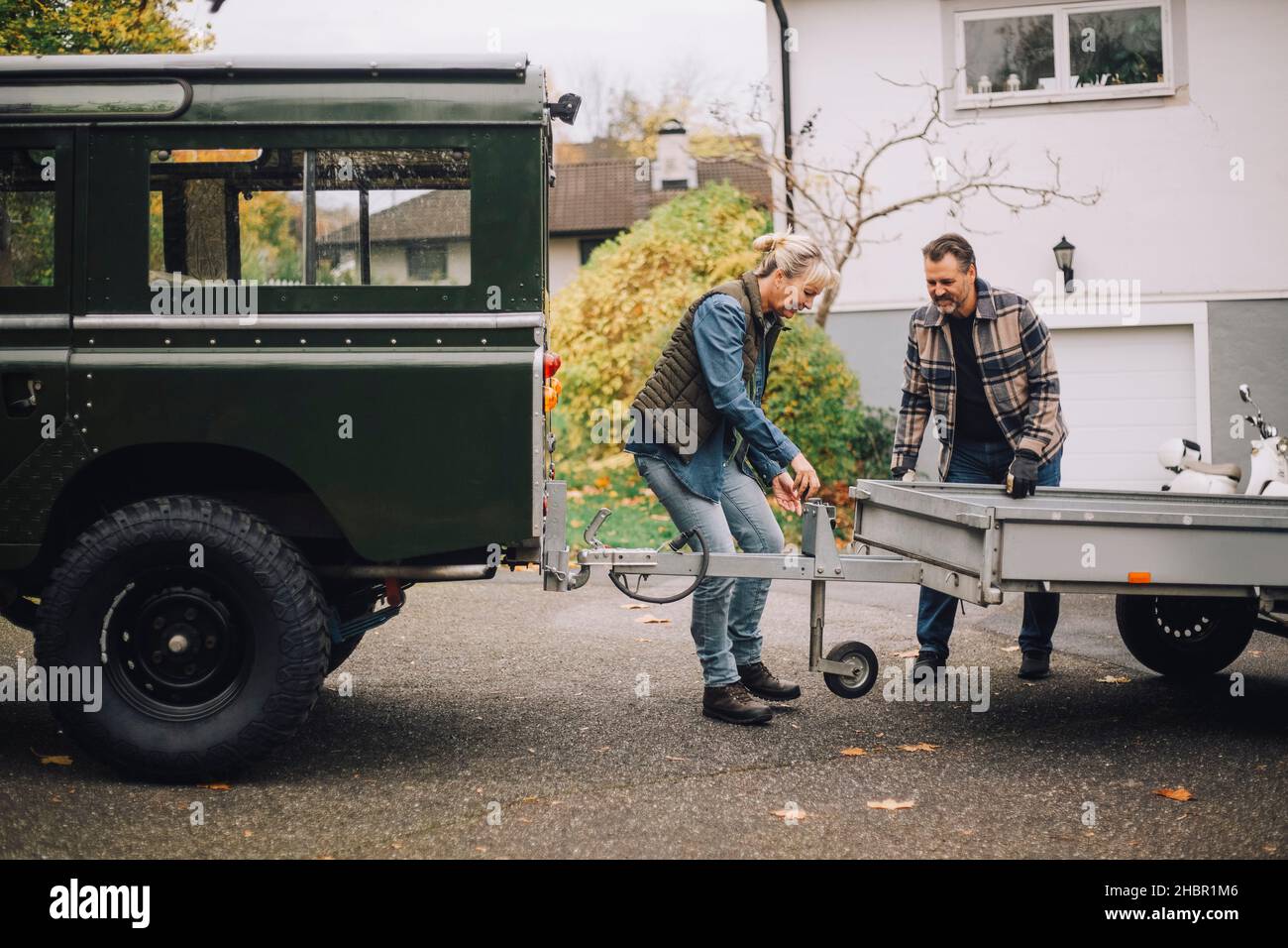 Mature couple towing trailer to sports utility vehicle on driveway Stock Photo