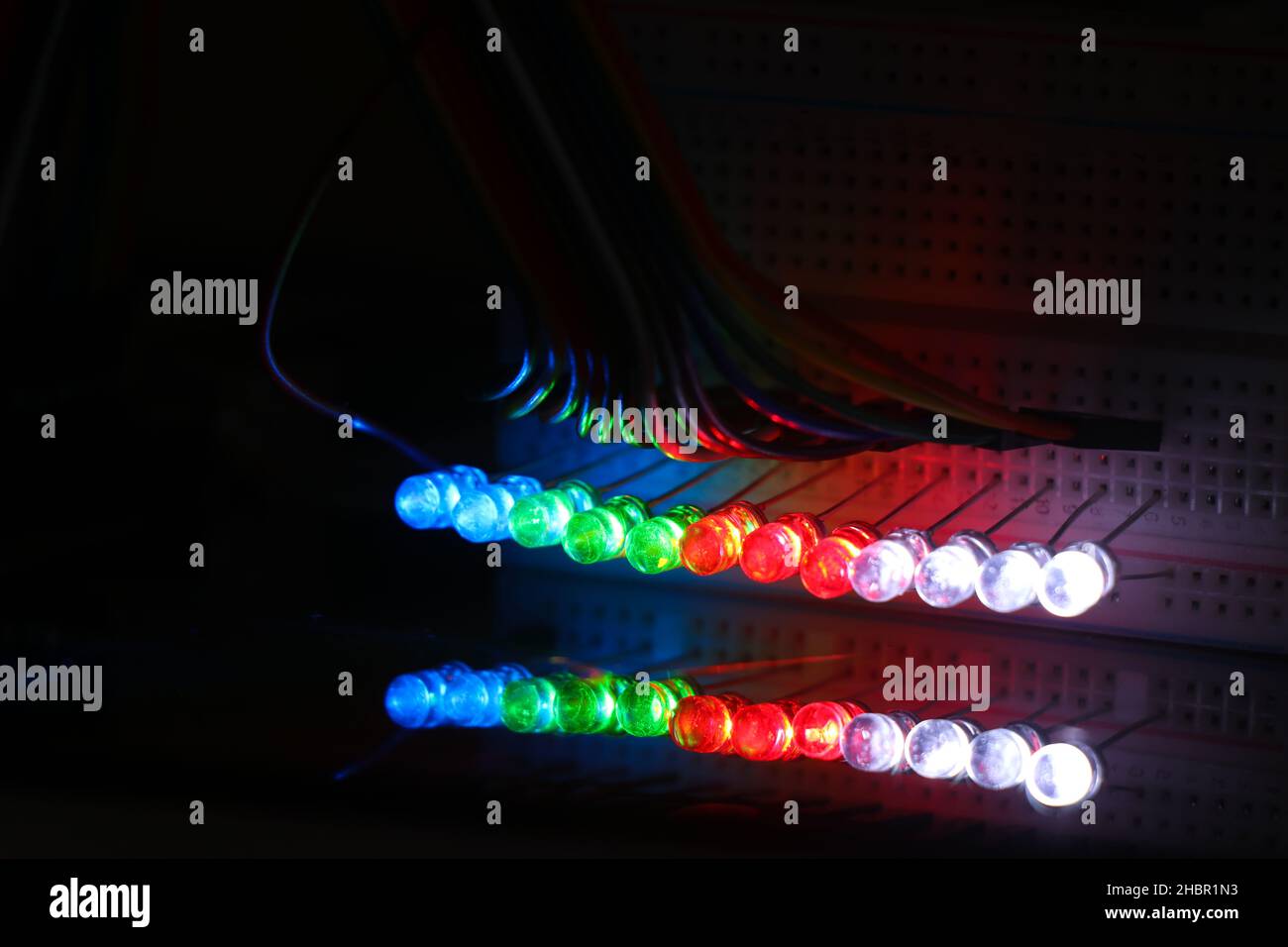 Glowing Light emitting diodes with reflections on the glass, LED bulbs displaying colorful lights Stock Photo