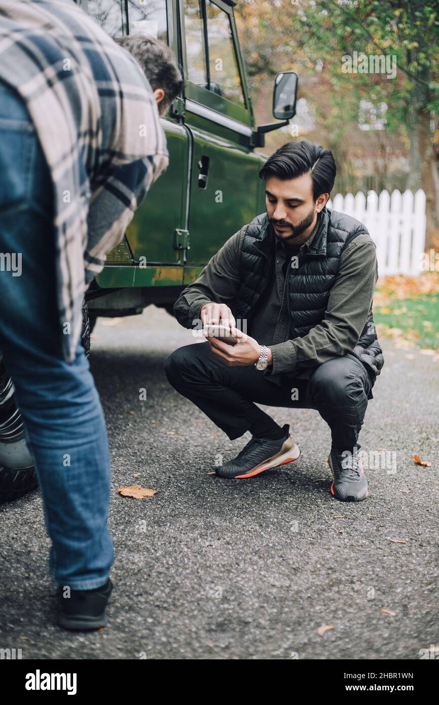Father by son using smart phone on driveway Stock Photo