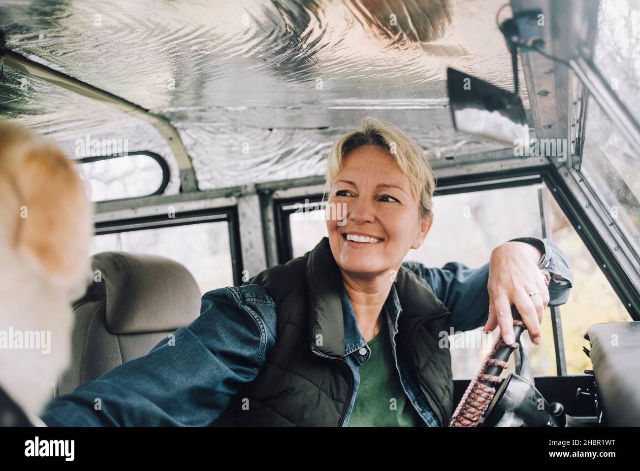 Smiling woman looking away while sitting in sports utility vehicle Stock Photo