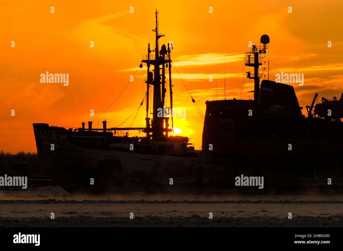 Silhouette of an icebreaker on a sunset background. Steam from water during severe frost Stock Photo