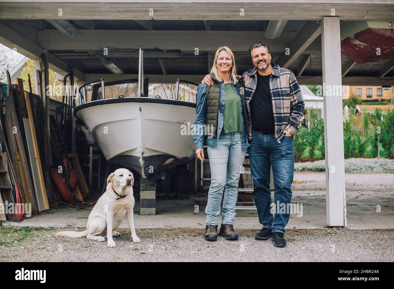 Smiling mature couple with dog in garage Stock Photo - Alamy