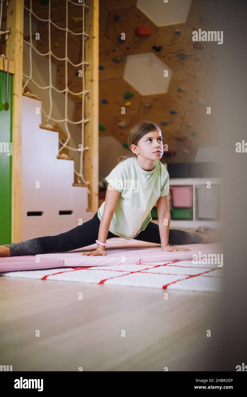 Female athlete looking away while doing stretching exercise at home Stock Photo