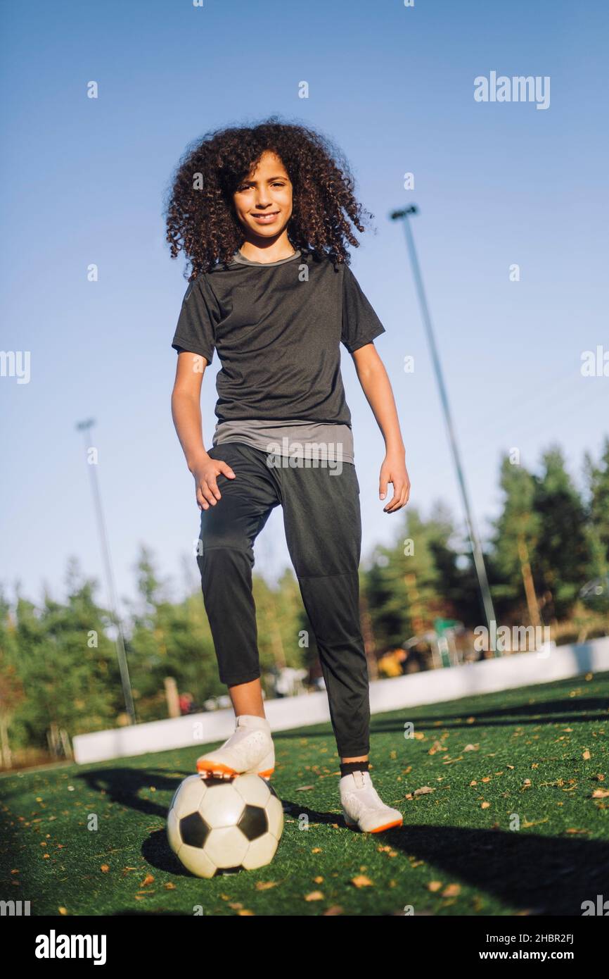 Portrait of girl with soccer ball on sports field during sunny day Stock Photo