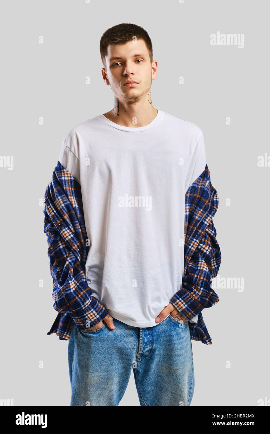 Young cocky man in shirt and jeans with hands in his pockets Stock Photo